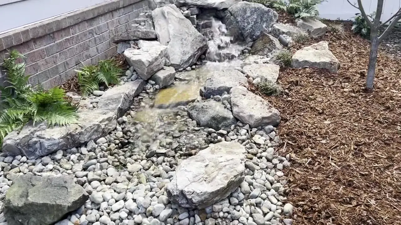 A boulder rock garden against a block wall