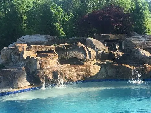 A boulder waterfall spilling into a swimming pool