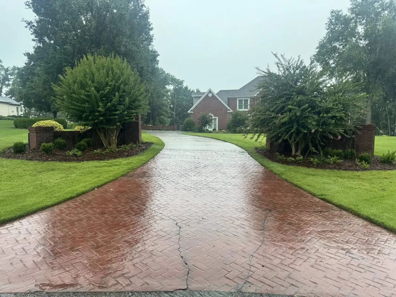 A brick driveway between mulched beds