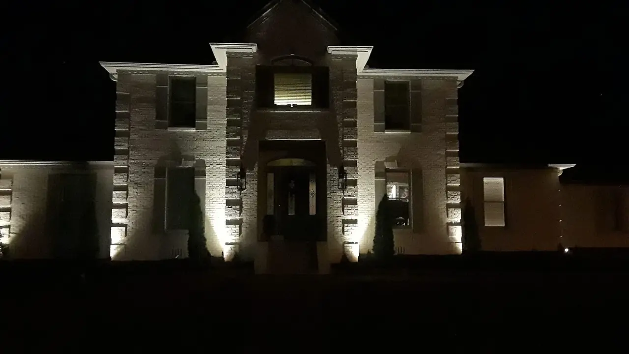 Columns and gables uplit on a white house after dark