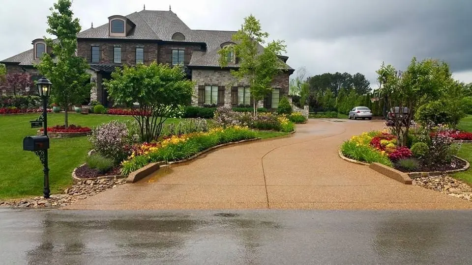 A curving drive with flower beds at a stone house