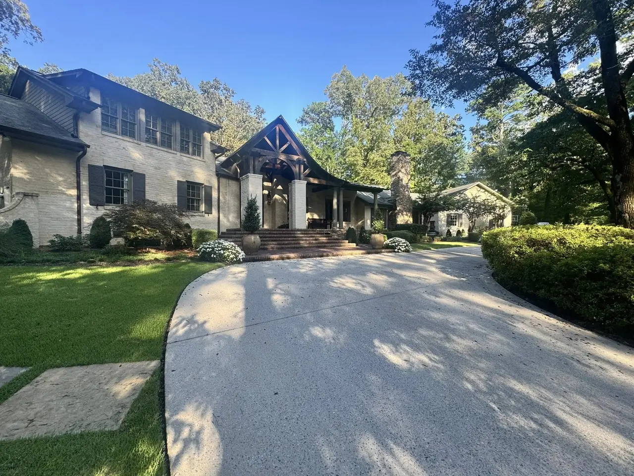 A curving driveway and beds at a stone house