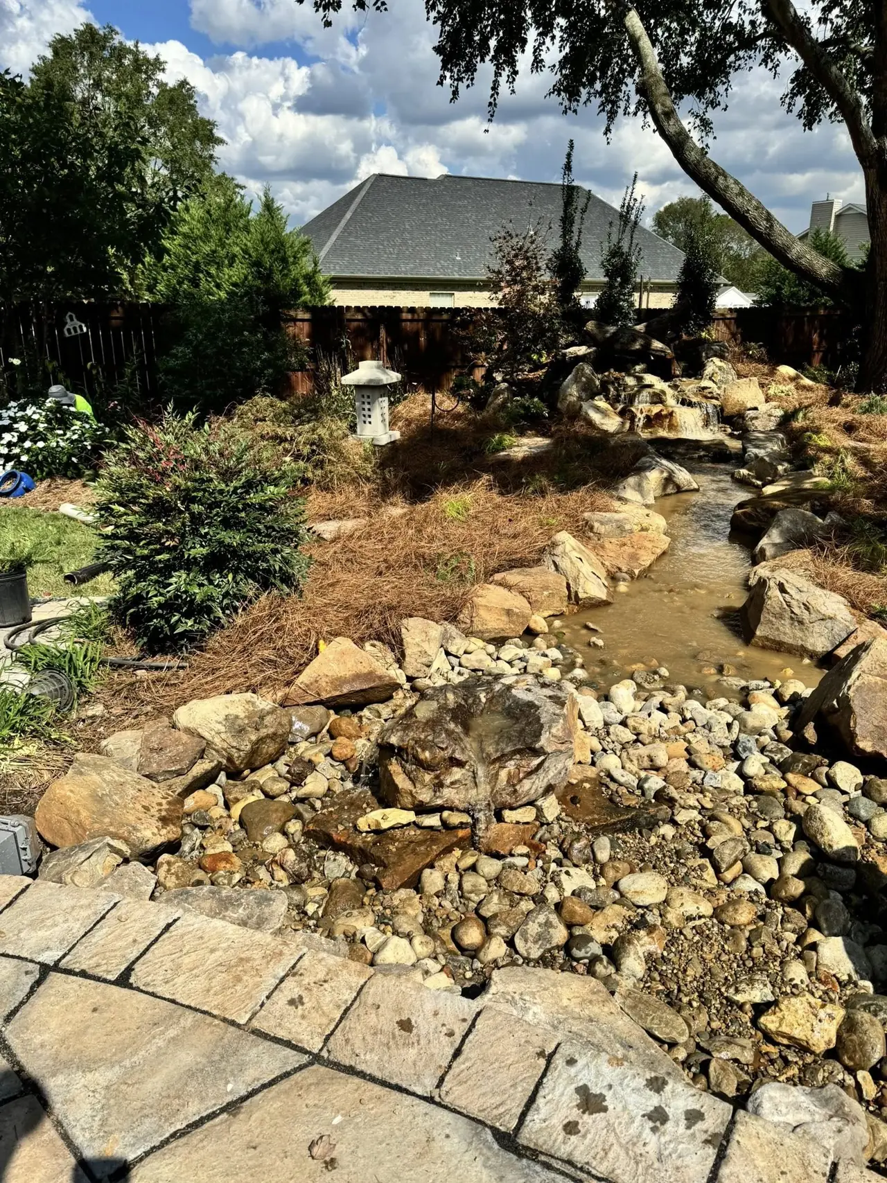 Dark urn fountains in a dry creek beside a walkway