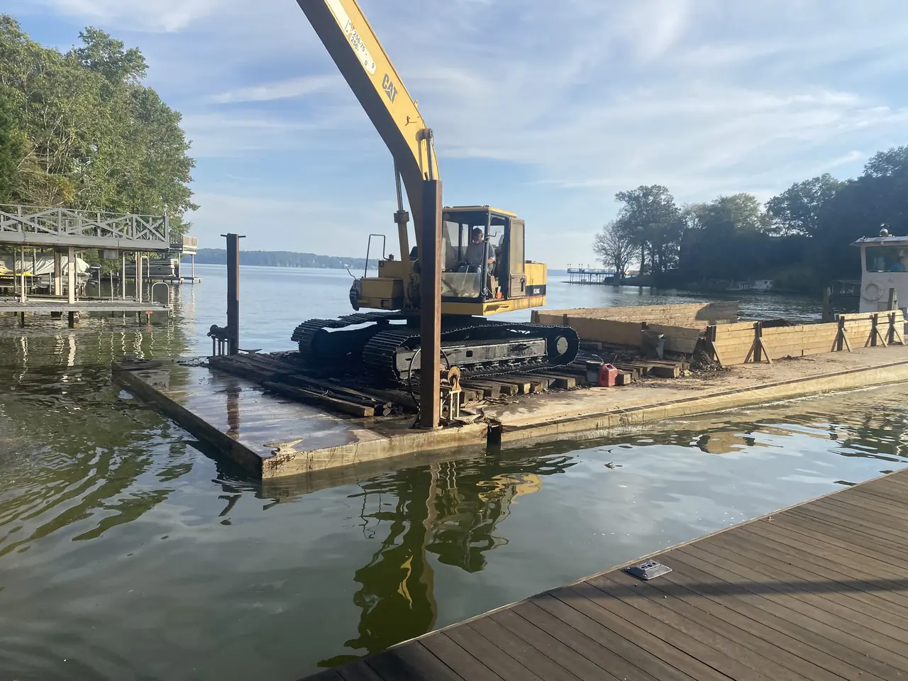 An excavator working from a barge at a lakeshore