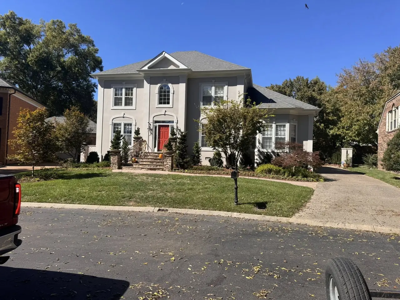 A front lawn and beds at a brick house with a red door