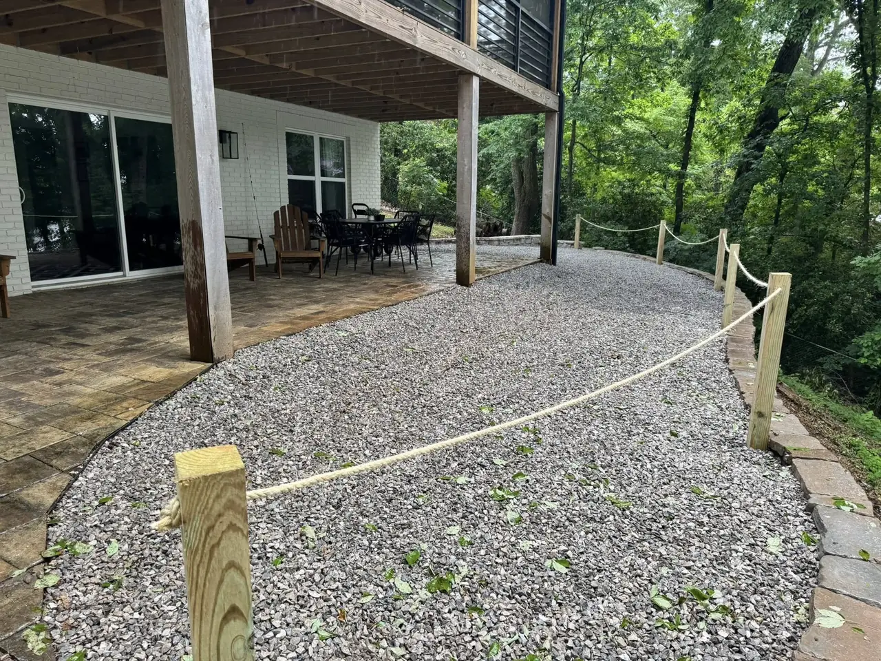 A gravel path with a rope rail beneath a deck