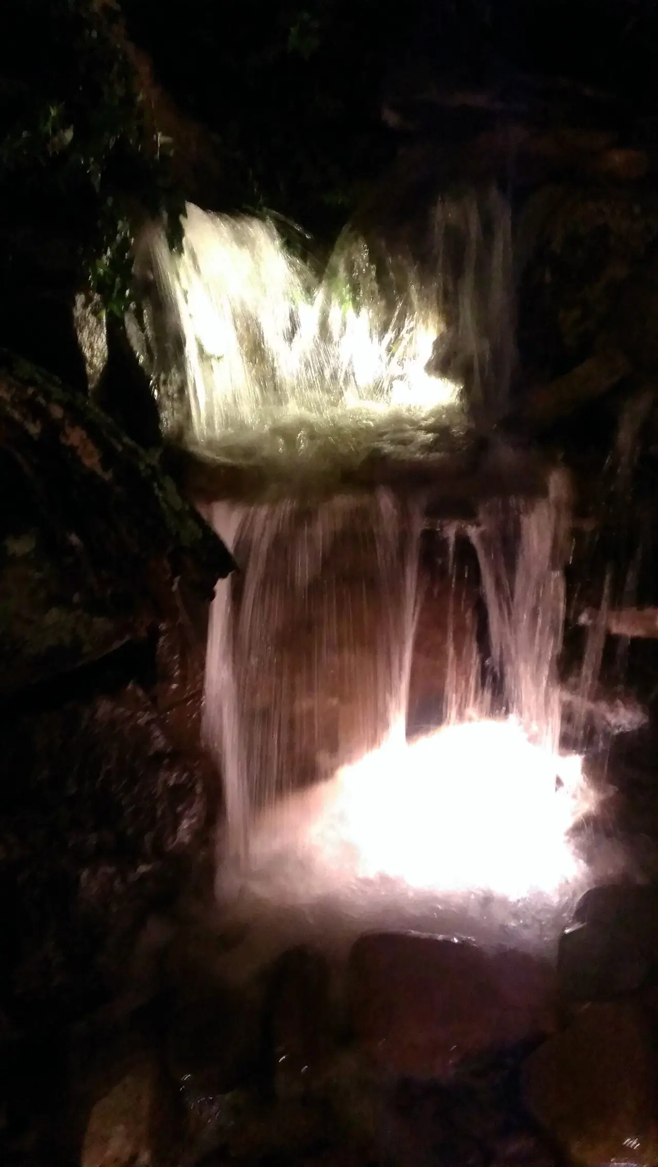 A lit waterfall glowing at night