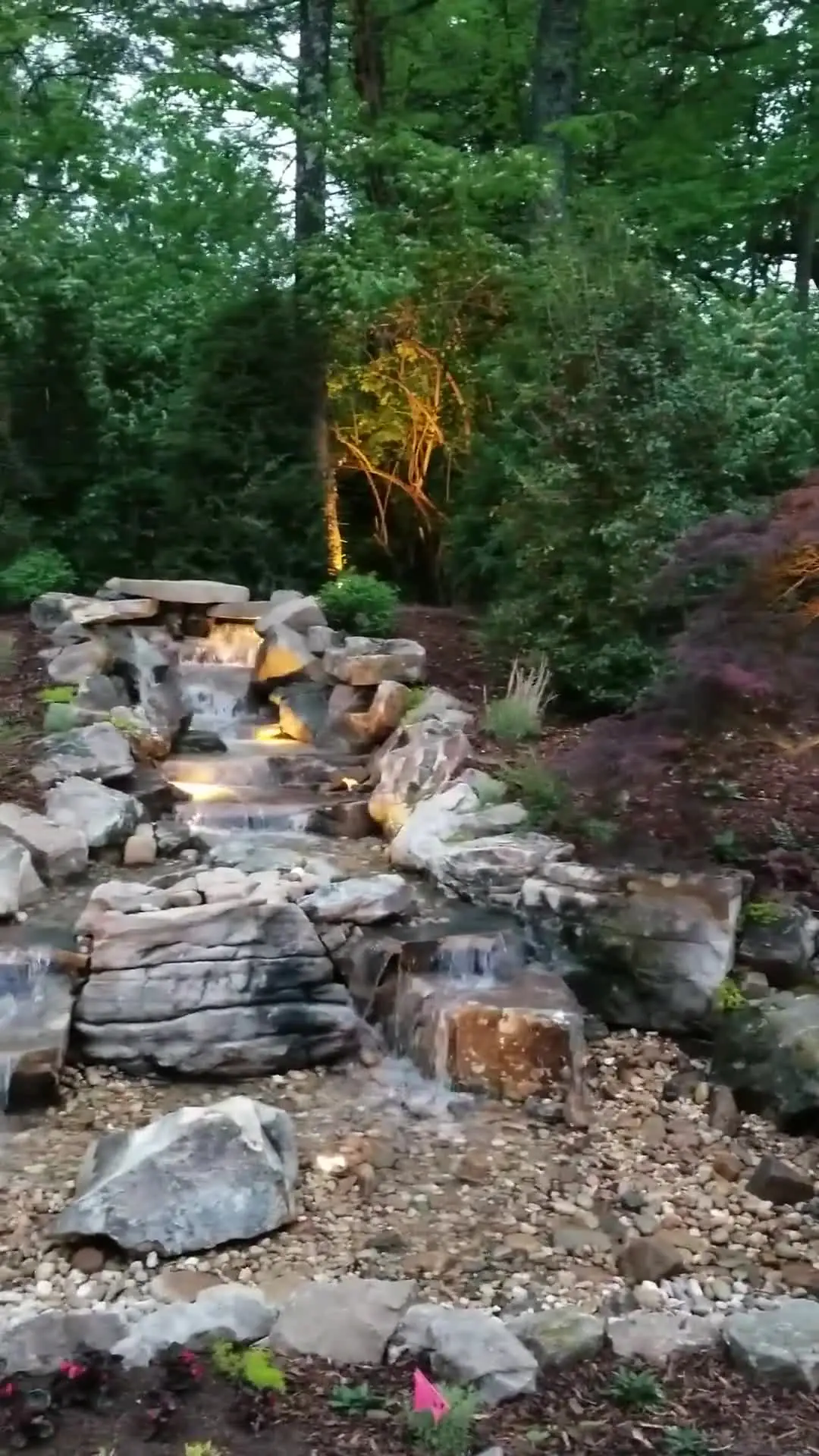 A narrow waterfall falling through rock under trees