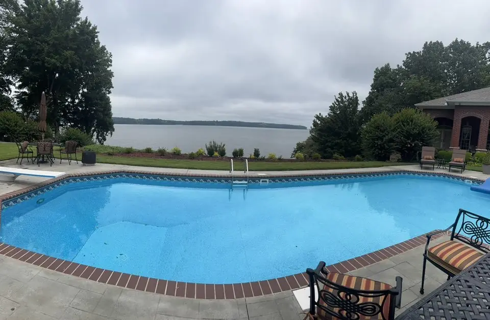 A pool deck and lawn above the lake