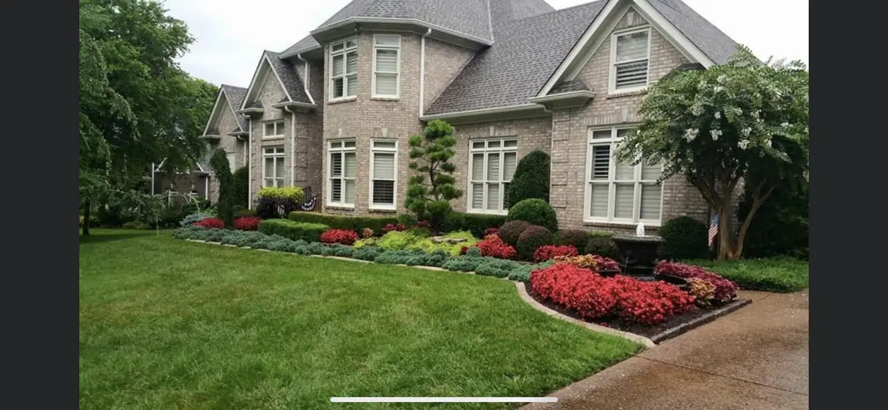 Red flower beds and a clipped lawn at a brick house