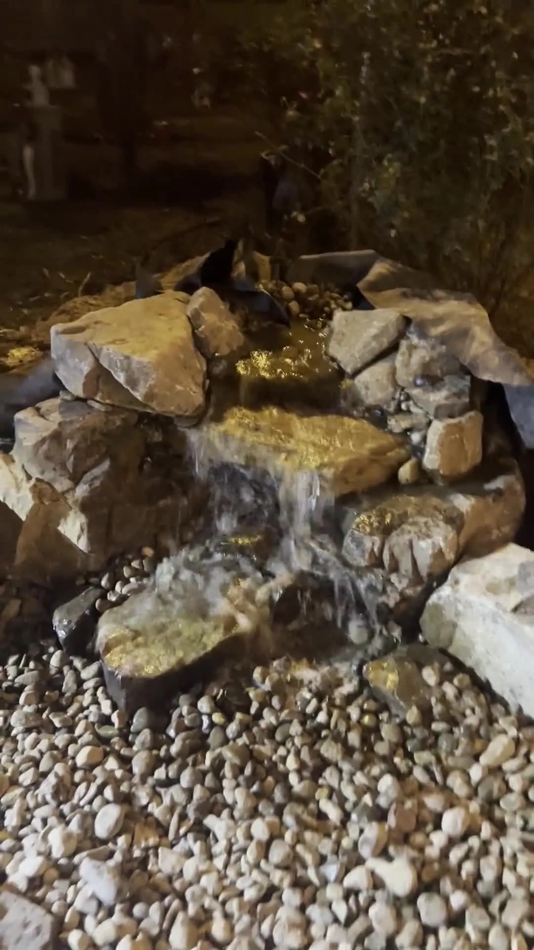 A small stacked-rock waterfall lit at night