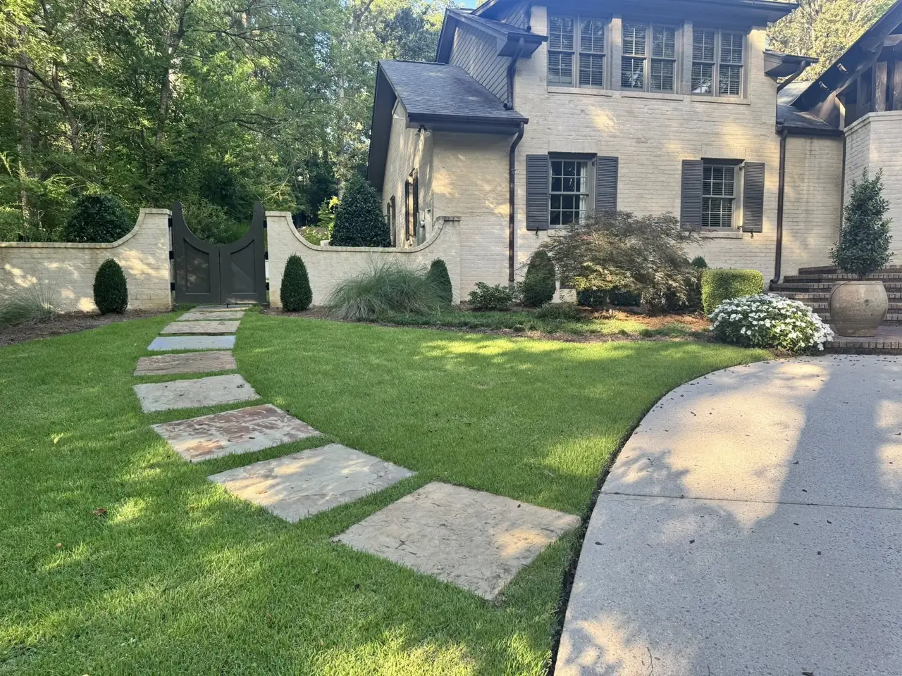 Stepping stones across a lawn to a stone house