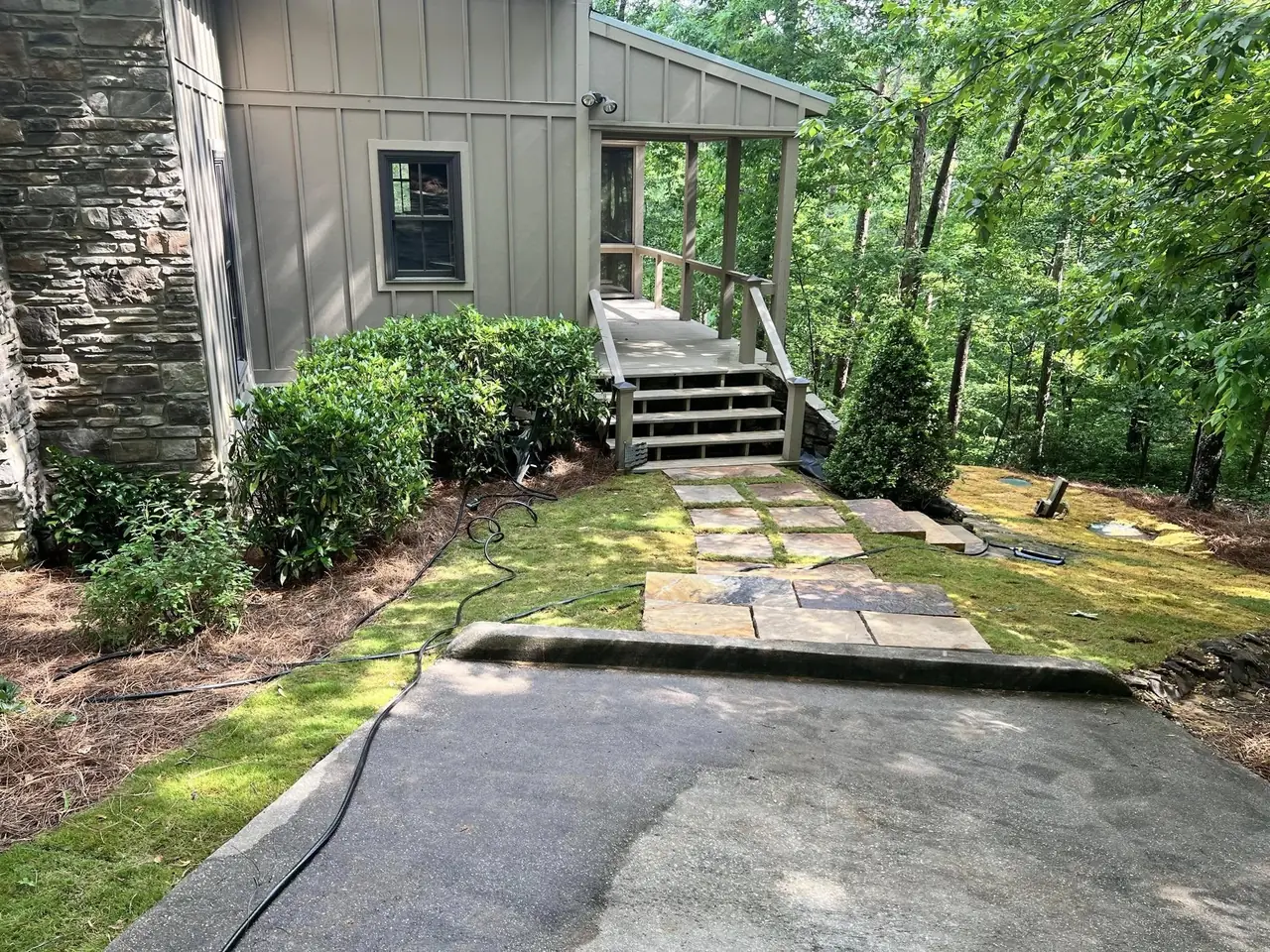 A stone path and new shrubs by a board-and-batten house
