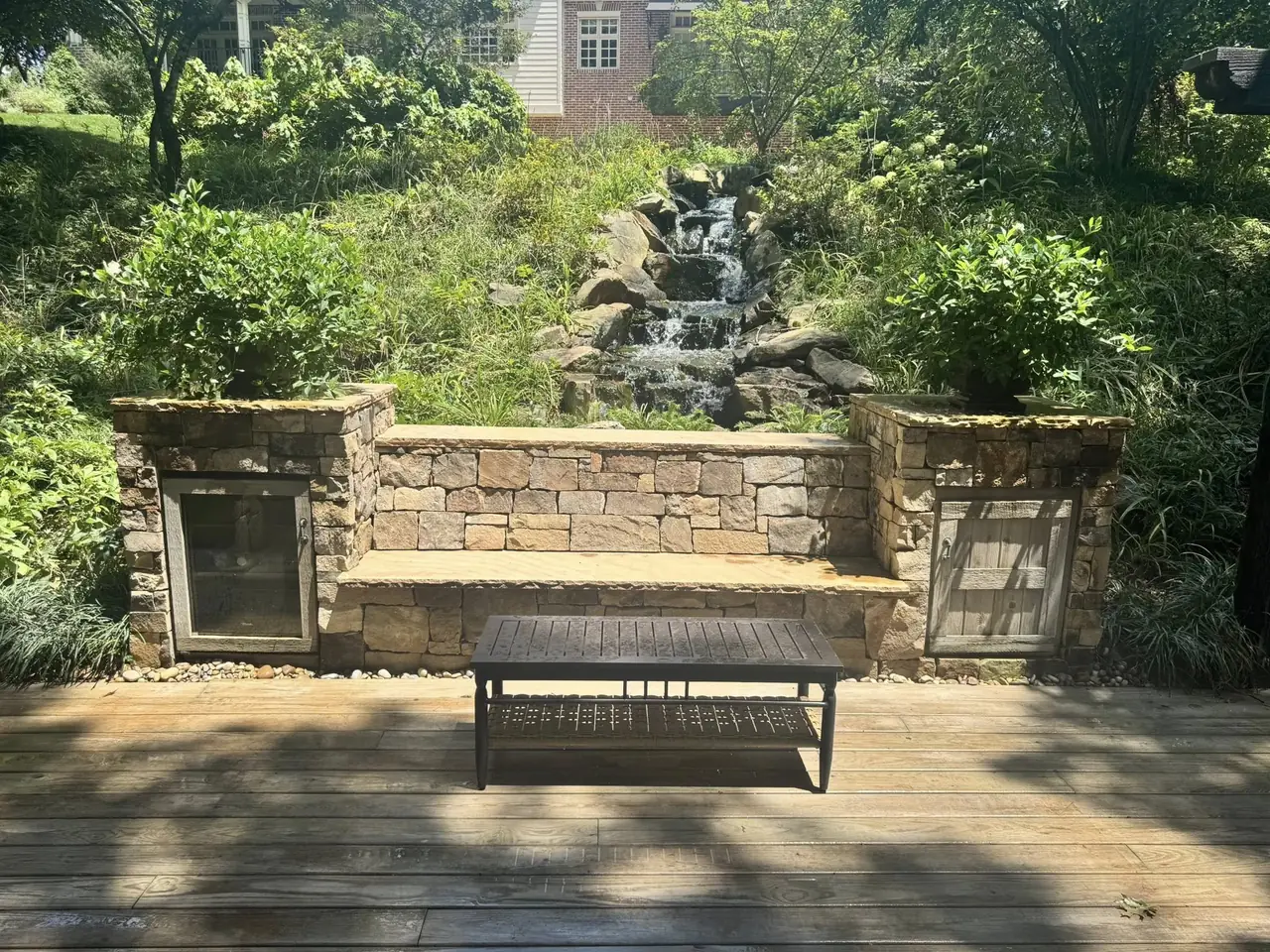 A waterfall behind a stone seat wall on a deck