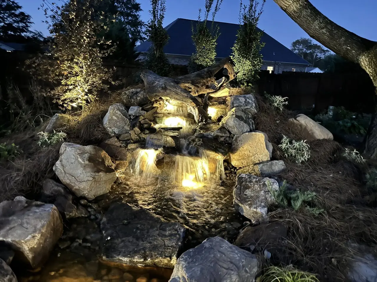 A wide rock waterfall lit at night
