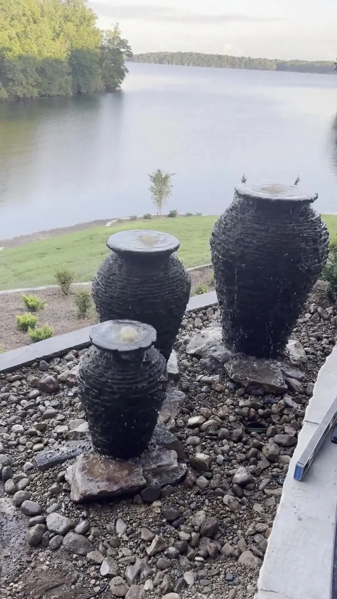 Three dark urn fountains set in river rock above a lake