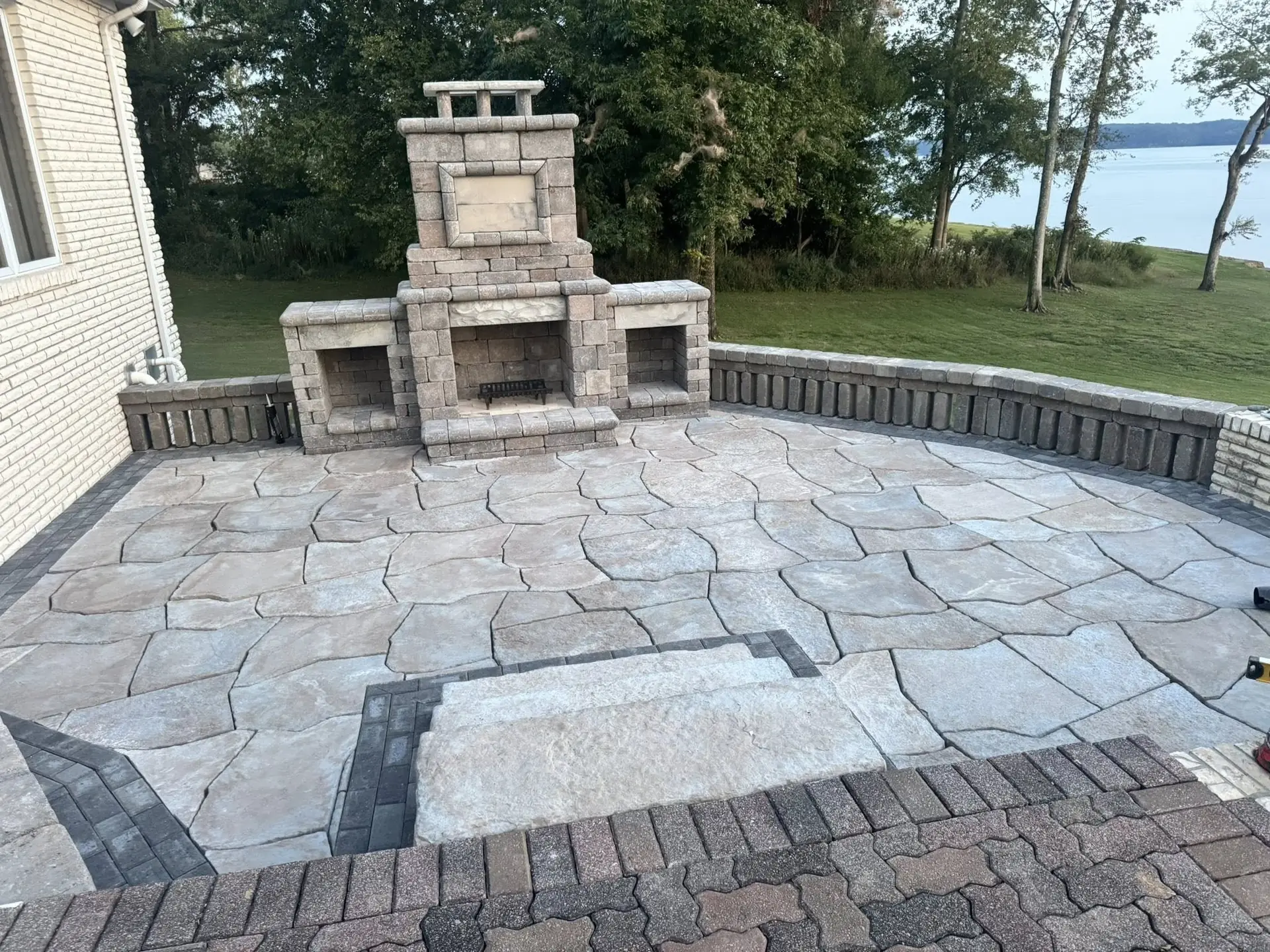 Flagstone patio with a stone outdoor fireplace above the lake