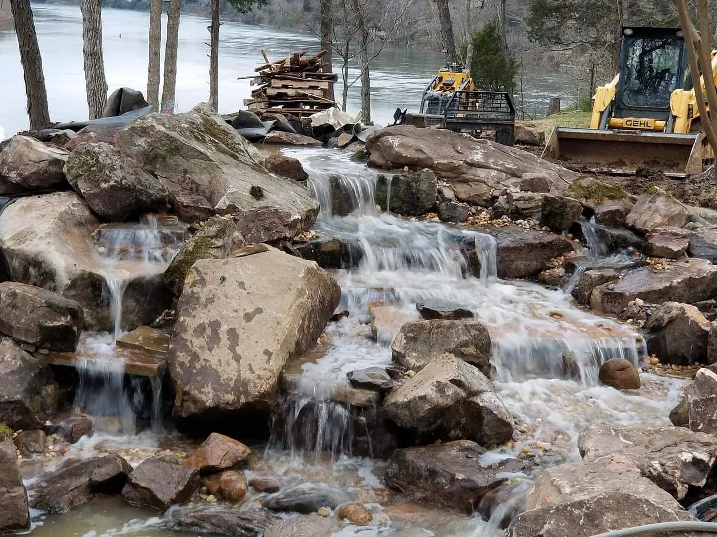 A wide multi-tier waterfall running for the first time, machines still on site