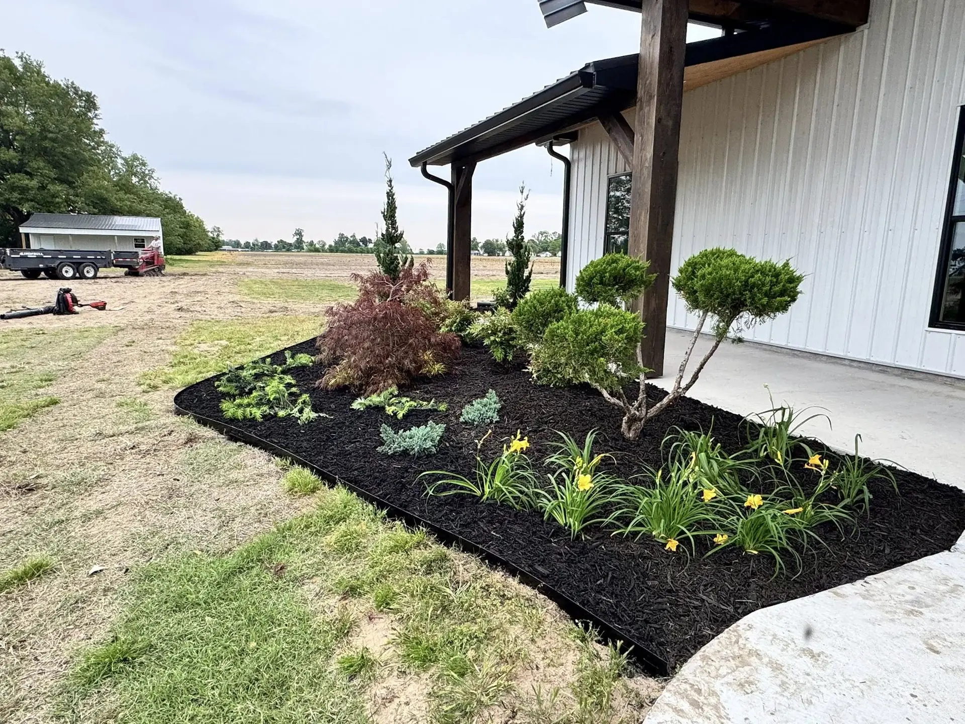 New planting beds with fresh mulch beside a farmhouse porch