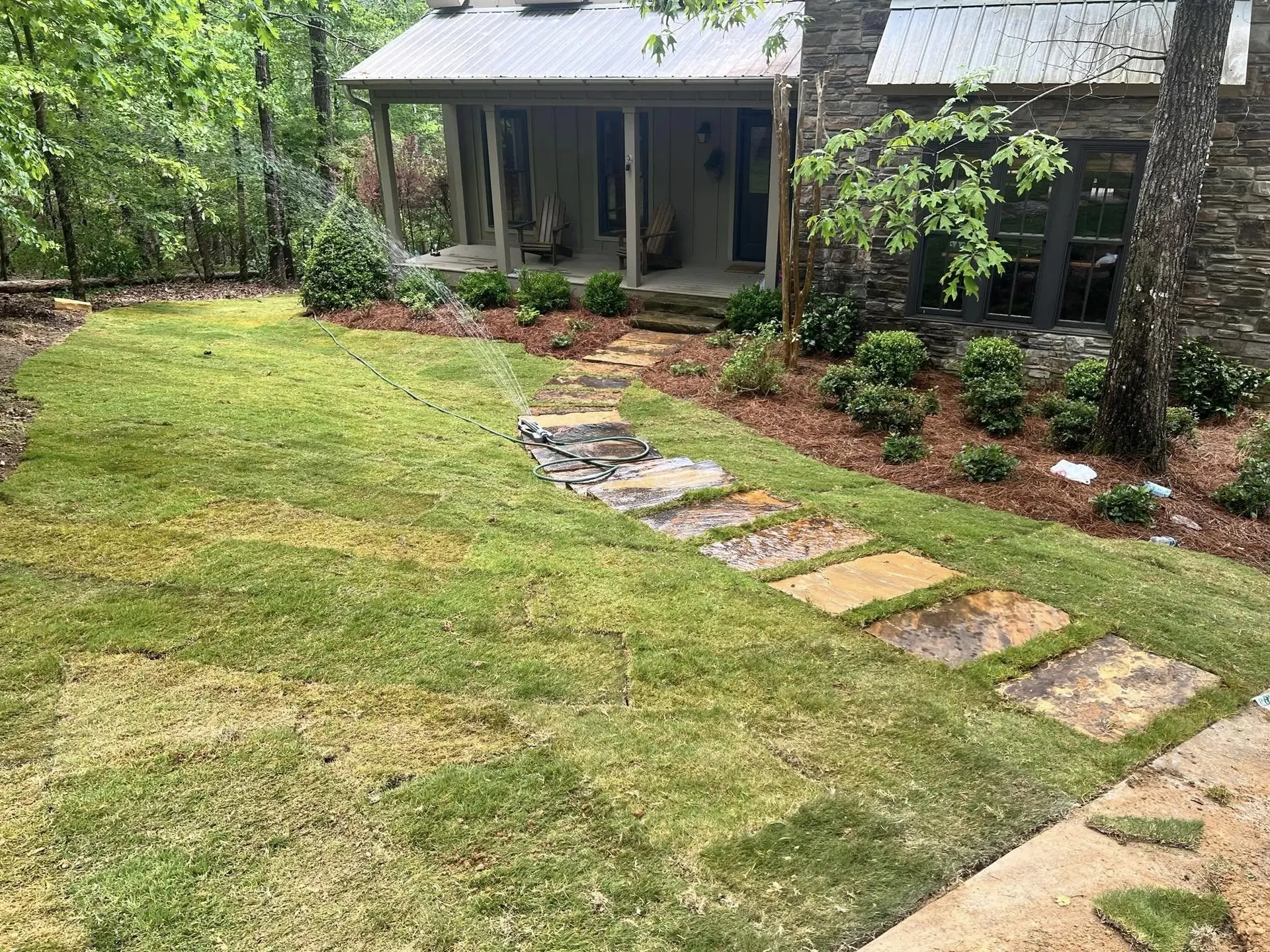 New sod and stepping stones in front of a wooded cabin