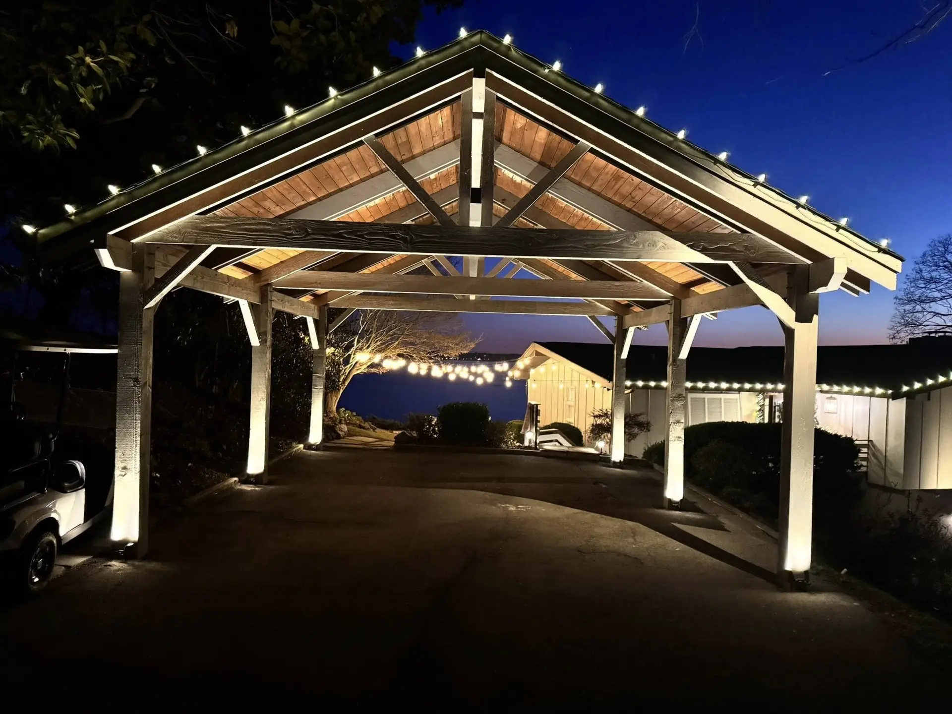 A timber pavilion with its posts and ceiling lit at night