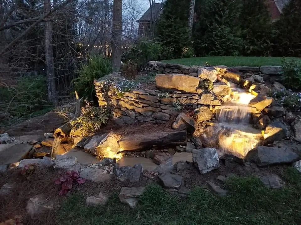 A stacked-stone waterfall lit at night