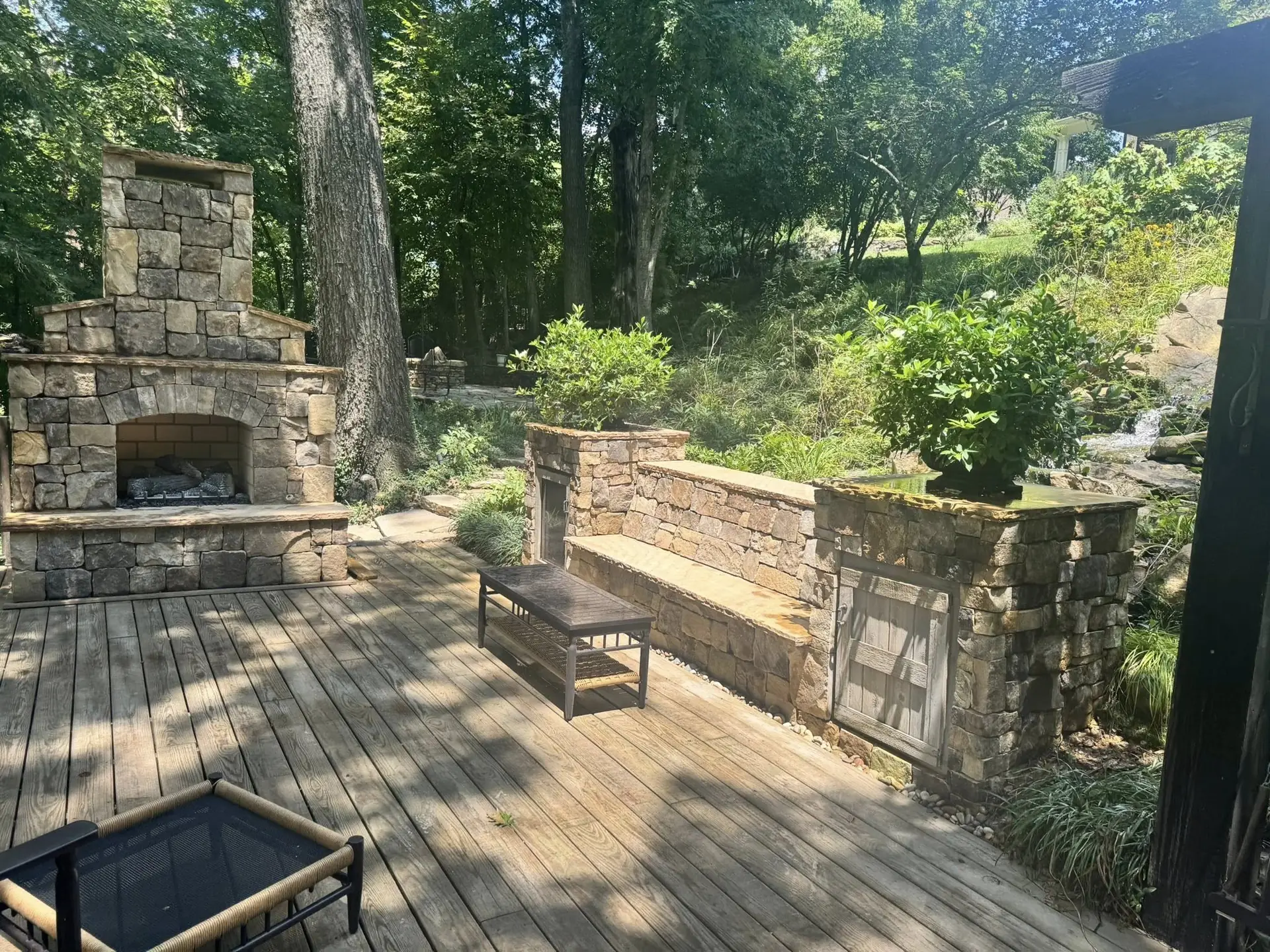 A stone fireplace and matching stone planters on a wooded deck