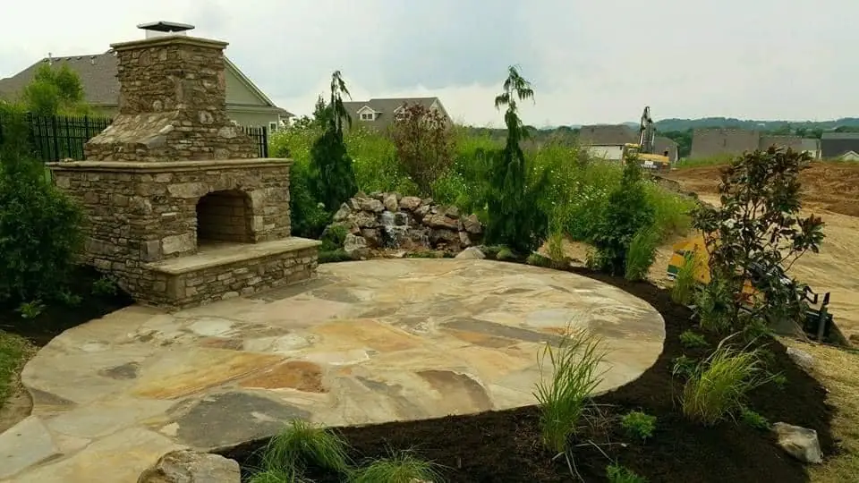 A stacked-stone fireplace facing a round flagstone patio
